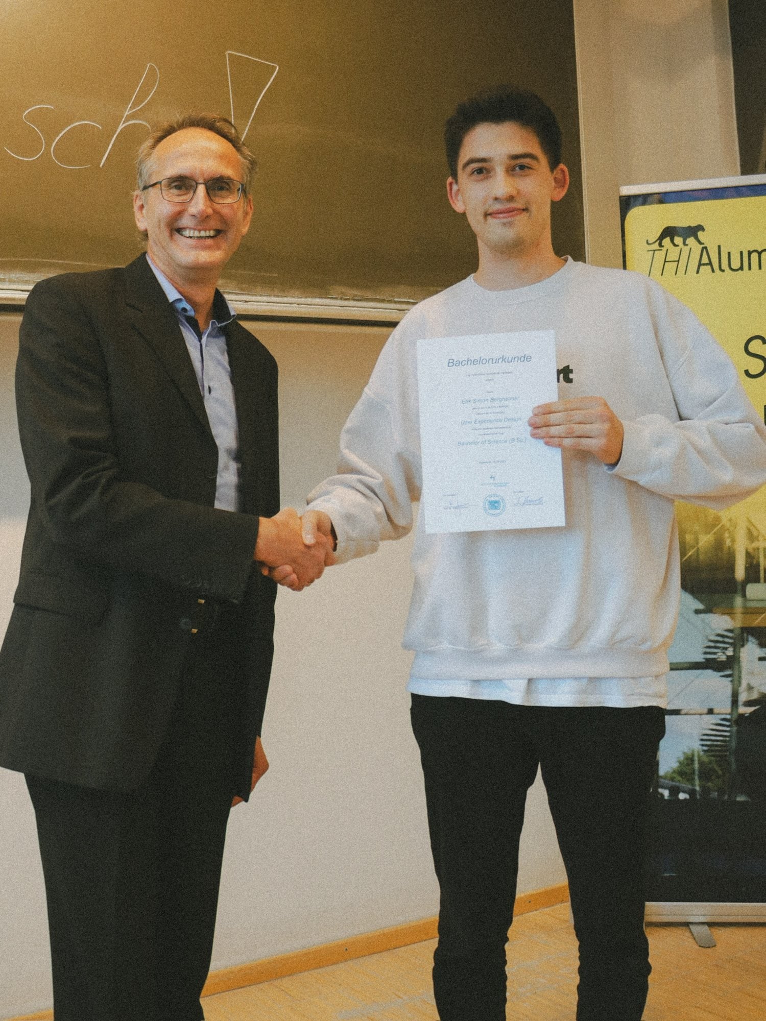 Erik receiving his Bachelor of Science certificate in User Experience Design with a handshake